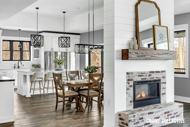 dining space featuring dark wood-style floors, baseboards, and a fireplace