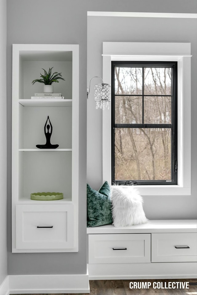 mudroom with dark wood-style flooring and built in shelves