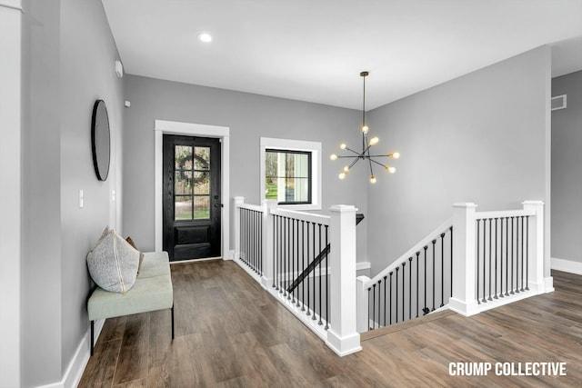 entryway with visible vents, a notable chandelier, baseboards, and wood finished floors