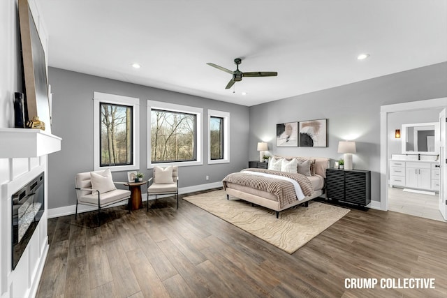 bedroom featuring baseboards, a glass covered fireplace, recessed lighting, and wood finished floors