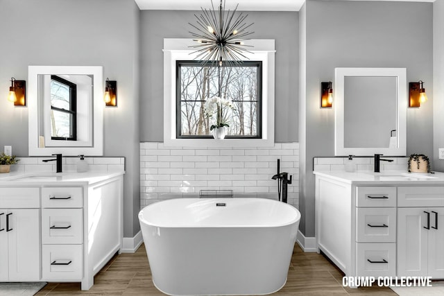 bathroom featuring tile walls, a notable chandelier, a sink, and two vanities