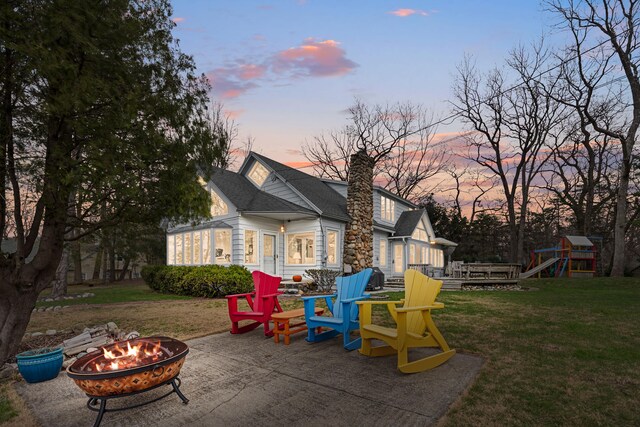 4117 Lake Shore Dr, New Buffalo, MI 49117 - playground at dusk featuring a playground, a deck, a yard, a patio, and an outdoor fire pit