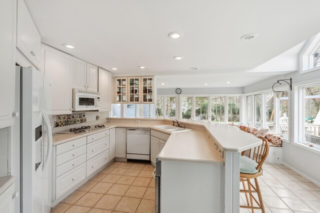 4117 Lake Shore Dr, New Buffalo, MI 49117 - kitchen with a peninsula, light tile patterned floors, a sink, and white appliances