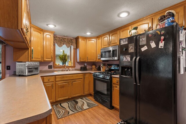 33028 Pokagon Hwy, Niles, MI 49120 - kitchen featuring a sink, a textured ceiling, light wood-style flooring, a toaster, and black appliances