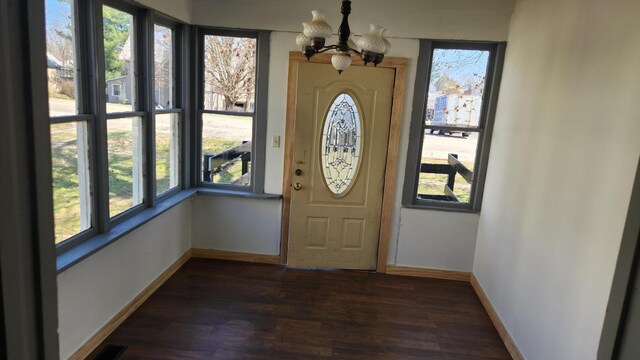 entrance foyer featuring baseboards, an inviting chandelier, dark wood-style floors, and plenty of natural light