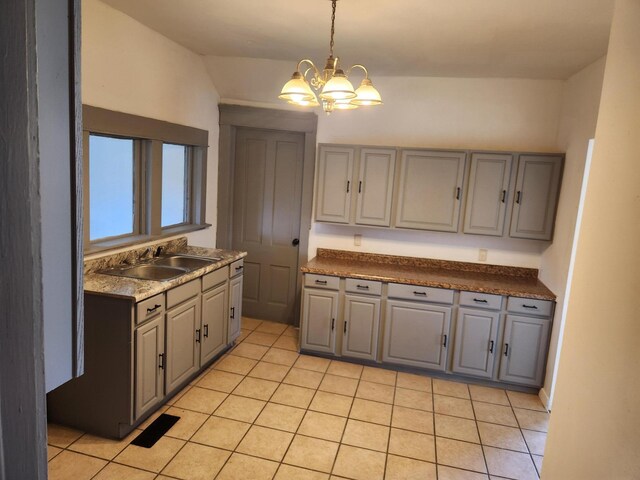 kitchen featuring a sink, light tile patterned floors, a notable chandelier, gray cabinetry, and lofted ceiling