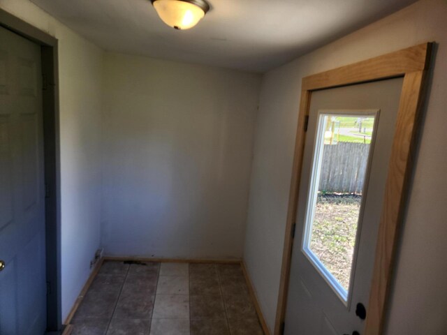 tiled empty room featuring baseboards