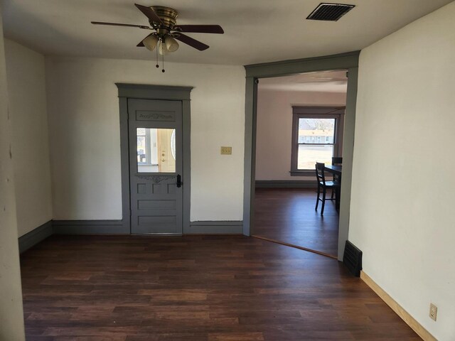 foyer entrance with dark wood-type flooring, visible vents, a ceiling fan, and baseboards