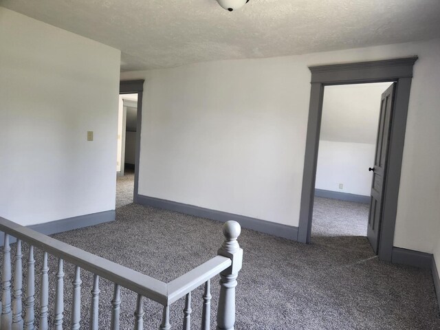 unfurnished room featuring a textured ceiling, carpet flooring, and baseboards