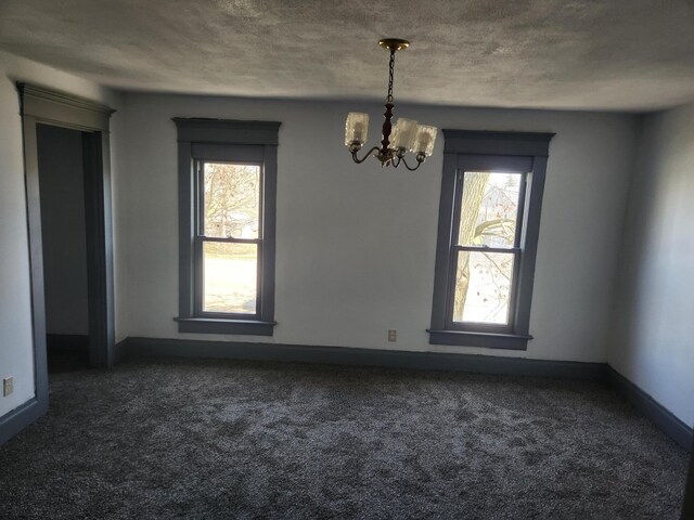 unfurnished dining area featuring baseboards, a notable chandelier, a healthy amount of sunlight, and dark carpet