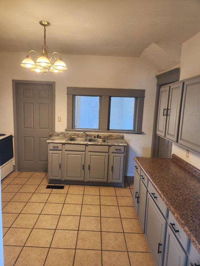 kitchen with range with electric cooktop, light tile patterned floors, a sink, gray cabinetry, and decorative light fixtures