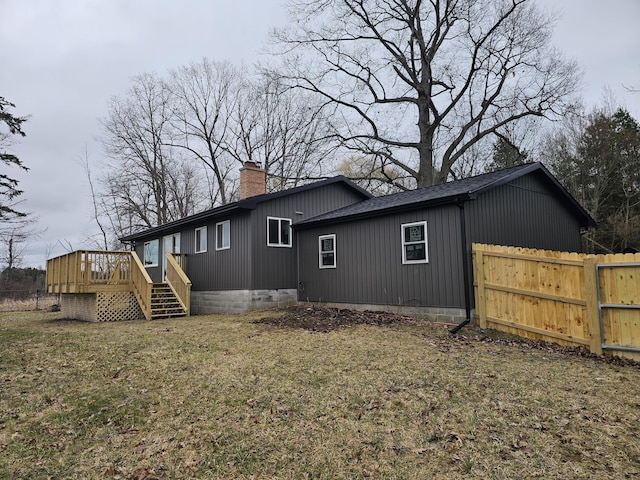 6162 Fuller Rd, Greenville, MI 48838 - view of side of home with a chimney, a wooden deck, fence, and a yard
