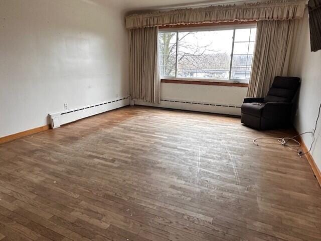 interior space with a baseboard radiator, baseboards, and wood finished floors