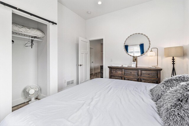 1641 N Arrowhead Rd, Mears, MI 49436 - bedroom featuring a barn door, visible vents, baseboards, and wood finished floors