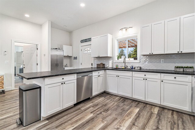 1641 N Arrowhead Rd, Mears, MI 49436 - kitchen with light wood-style floors, a peninsula, white cabinets, dishwasher, and backsplash