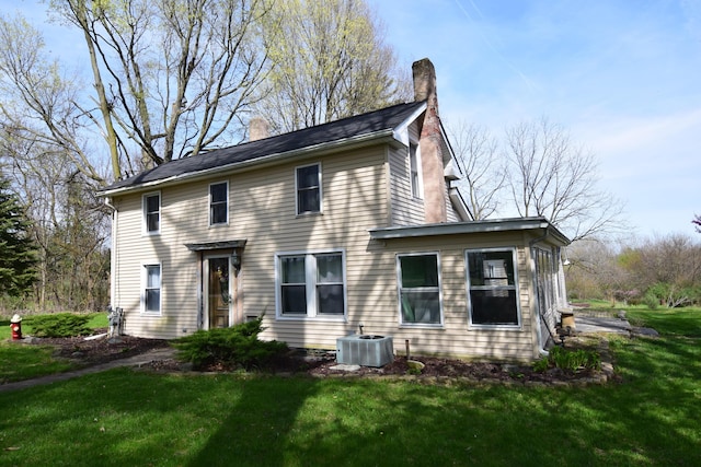 rear view of property with a yard, a chimney, and cooling unit