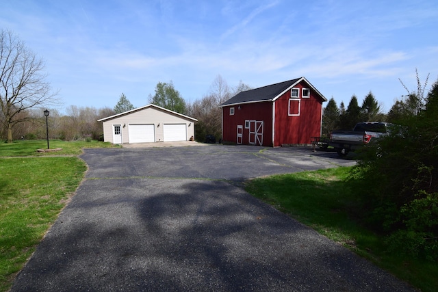 exterior space featuring an outdoor structure, a garage, a barn, and a yard