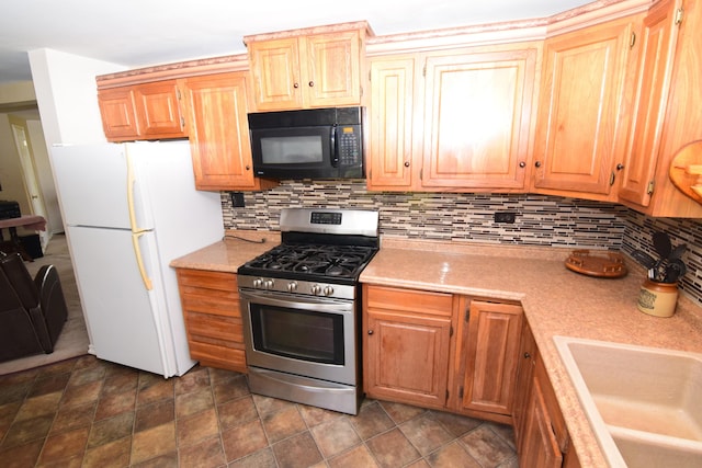 kitchen with freestanding refrigerator, black microwave, gas stove, and tasteful backsplash