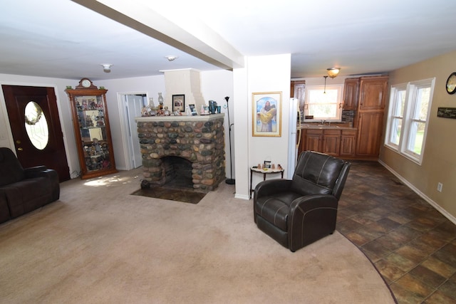 living area with baseboards and a stone fireplace