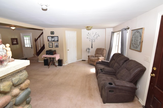 living area with baseboards, stairs, and light carpet