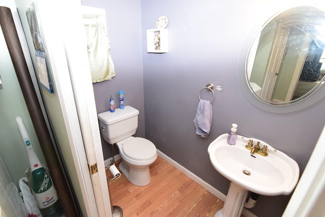 bathroom featuring toilet, baseboards, a sink, and wood finished floors