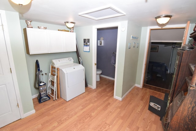 clothes washing area featuring baseboards, light wood-style flooring, cabinet space, and washer / clothes dryer