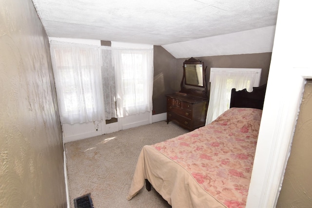carpeted bedroom featuring baseboards, vaulted ceiling, and visible vents