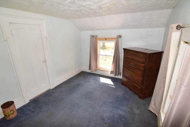 additional living space with a textured ceiling, vaulted ceiling, baseboards, and dark colored carpet