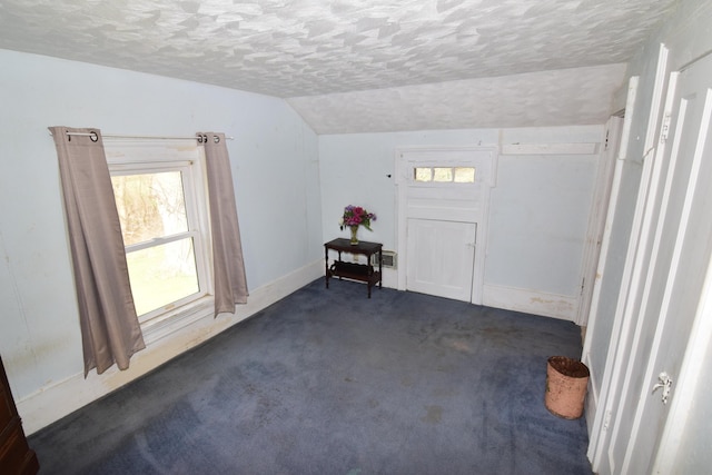 entrance foyer featuring baseboards, carpet flooring, a textured ceiling, and lofted ceiling