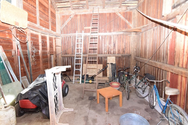 miscellaneous room with wood walls and unfinished concrete flooring