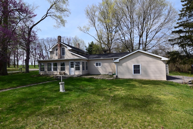 rear view of property featuring a chimney and a yard