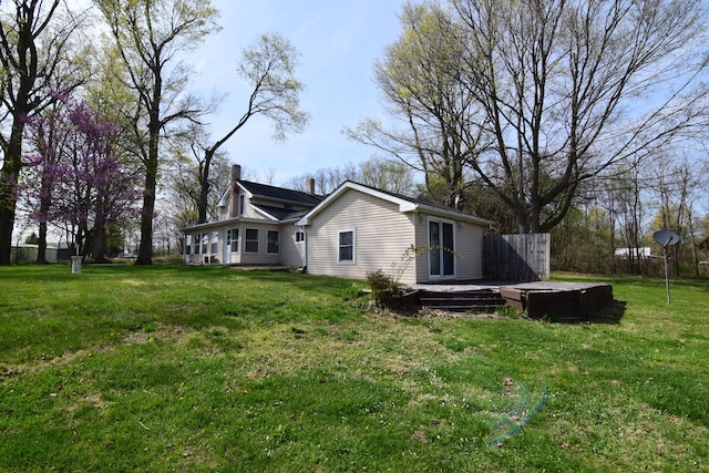 view of side of property with a yard, a deck, and a chimney