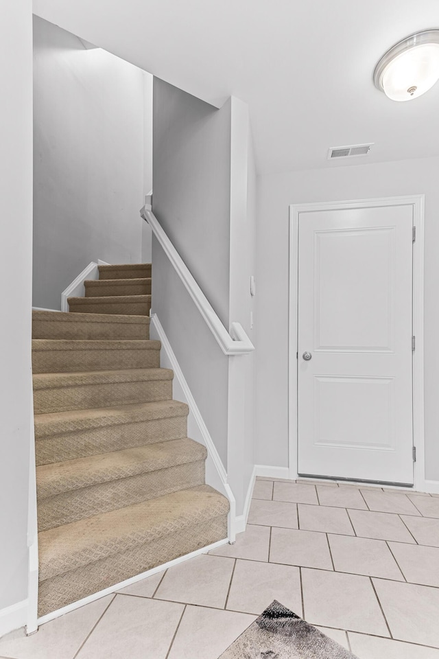 foyer with light tile patterned flooring, baseboards, stairway, and visible vents