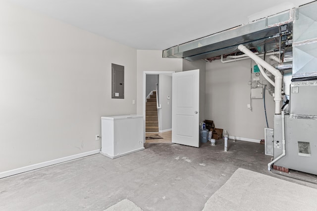 below grade area with electric panel, baseboards, fridge, and stairway
