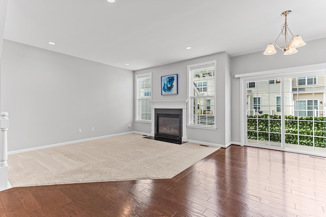 unfurnished living room with a fireplace with flush hearth, baseboards, a chandelier, and recessed lighting