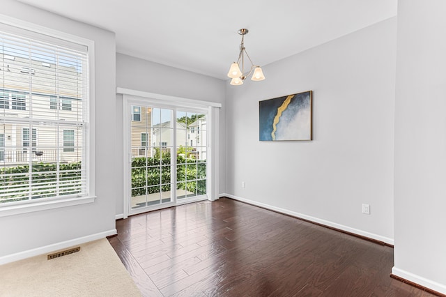 spare room with baseboards, visible vents, an inviting chandelier, and dark wood-style floors