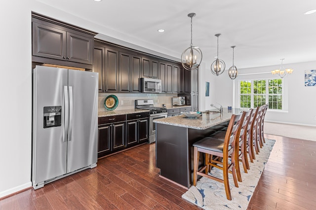 kitchen with light stone countertops, backsplash, a notable chandelier, and appliances with stainless steel finishes
