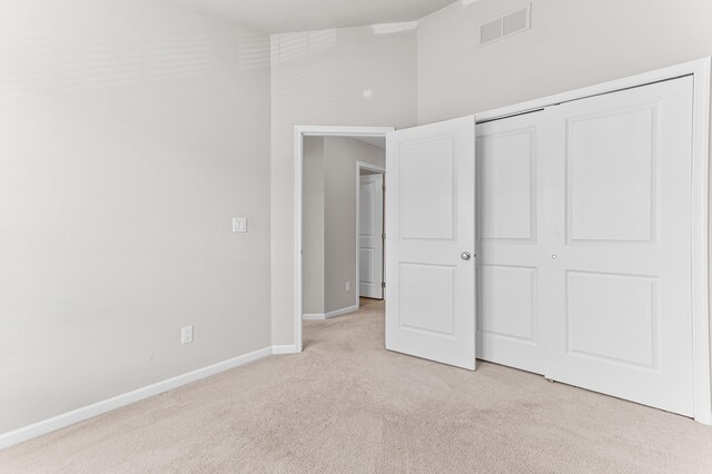 unfurnished bedroom with light colored carpet, visible vents, a closet, and baseboards