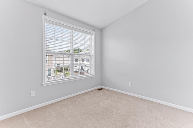 empty room featuring baseboards, vaulted ceiling, and carpet