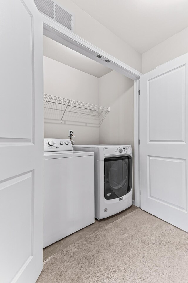 clothes washing area featuring independent washer and dryer, visible vents, light colored carpet, and laundry area