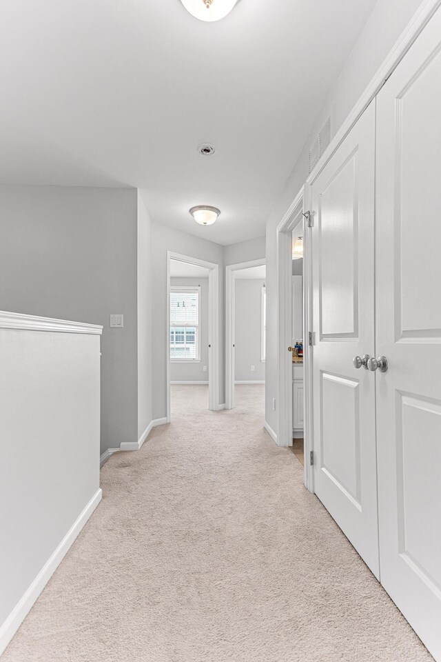 hallway featuring baseboards, visible vents, and carpet