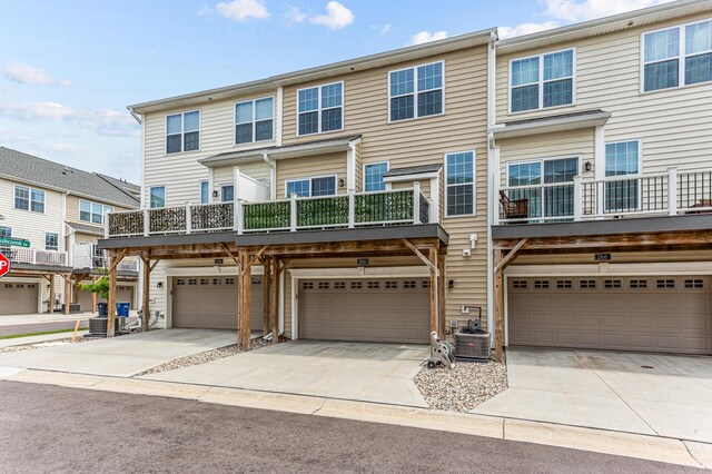 multi unit property featuring concrete driveway, a garage, and central air condition unit