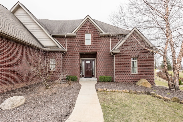 view of front of home featuring brick siding and a shingled roof