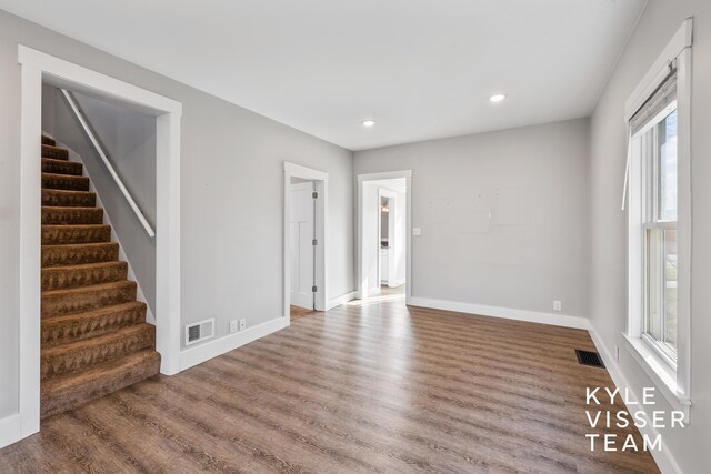 135 Houseman Ave NE, Grand Rapids, MI 49503 - unfurnished living room with baseboards, visible vents, stairway, and wood finished floors