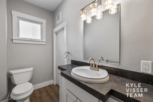 135 Houseman Ave NE, Grand Rapids, MI 49503 - half bath with visible vents, baseboards, toilet, wood finished floors, and vanity