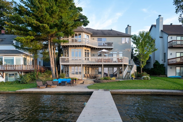 1761 S Shore Dr, Holland, MI 49423 - back of property with stairway, a chimney, a patio, a lawn, and a water view