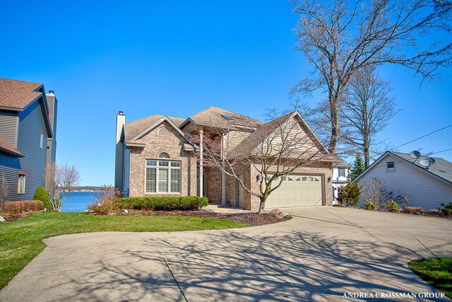 1761 S Shore Dr, Holland, MI 49423 - view of front facade featuring a front lawn, driveway, an attached garage, and brick siding