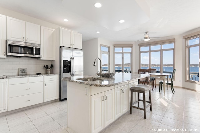1761 S Shore Dr, Holland, MI 49423 - kitchen with light stone countertops, stainless steel appliances, backsplash, and a ceiling fan