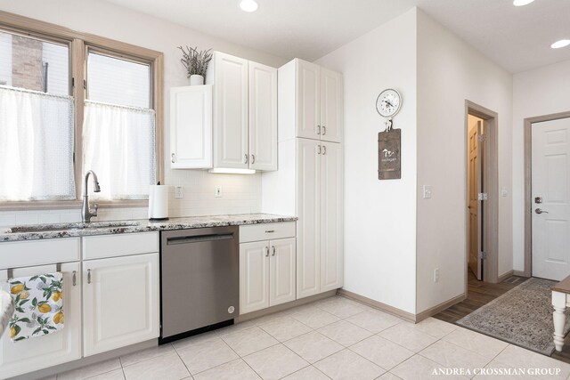 1761 S Shore Dr, Holland, MI 49423 - kitchen featuring white cabinets, dishwasher, baseboards, a sink, and light stone counters