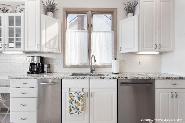 1761 S Shore Dr, Holland, MI 49423 - kitchen with white cabinetry, a sink, light stone counters, dishwasher, and glass insert cabinets